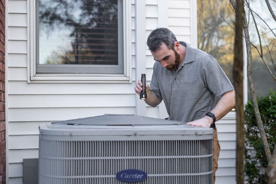 Technician diagnosing a home AC condenser unit